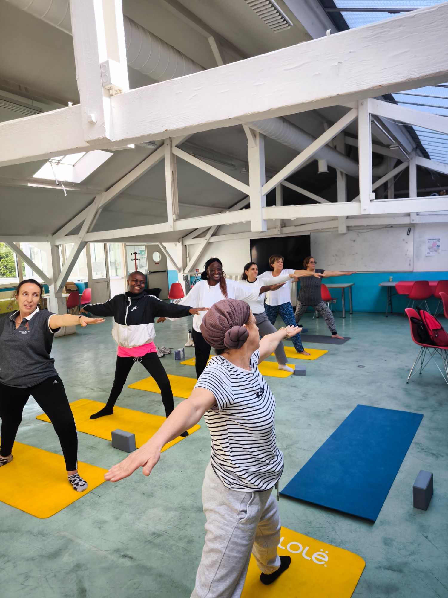 Cours de yoga dans un loft lumineux, posture du guerrier